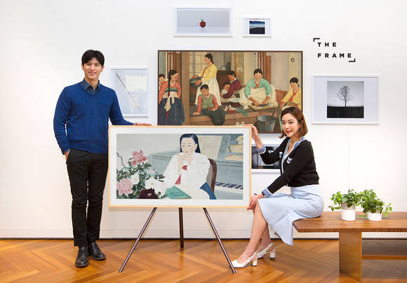 삼성전자 모델이 '더 프레임' TV를 통해 국립현대미술관의 '신여성 도착하다' 展 작품을 소개하고 있다. TV 속 작품은 이유태 작가의 '화운'이고, 벽 가운데 걸린 그림은 김중현 작가의 '춘양'이다. (사진 = 삼성전자)